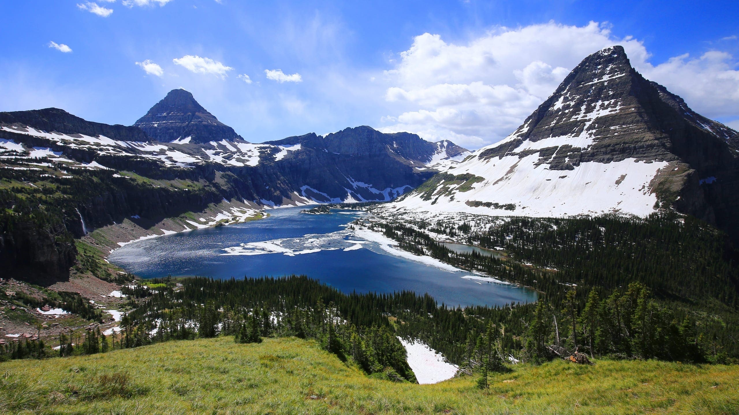 A view of a lake between two snow covered mountains in the beautiful Glacier National Park