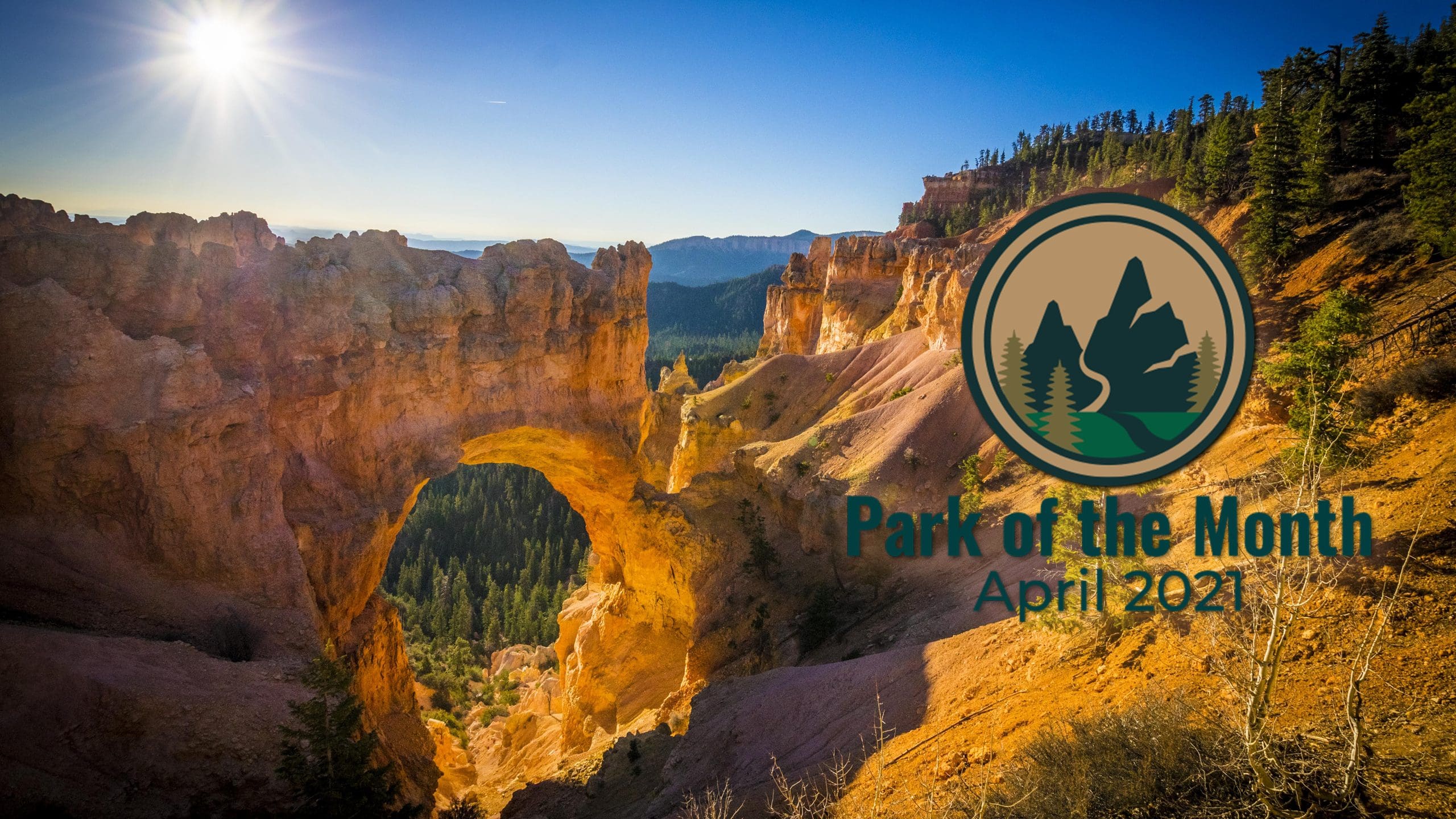 A view of The Natural Bridge with trees on the nearby cliff faces, the sun rising and the mountains in the distance