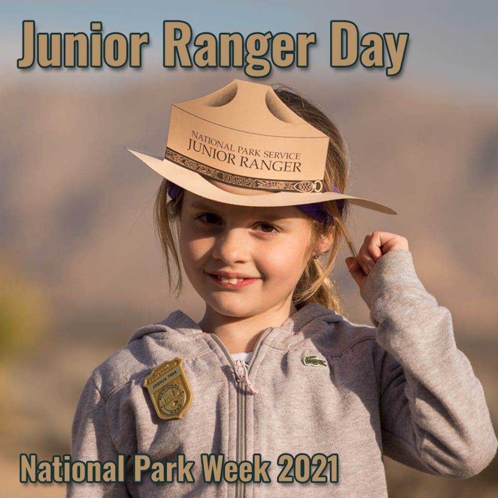 A young female child stands with her pin and a paper cutout Park Ranger hat